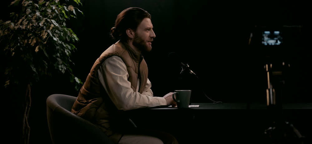 Concept image: a warm, dark podcast studio with a microphone on a table